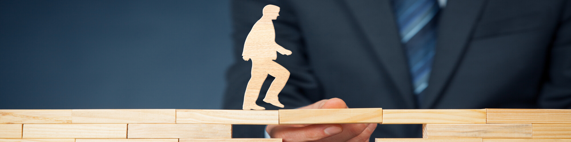 male figure walking on wooden jenga blocks 